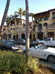 several cars parked in front of a building with palm trees