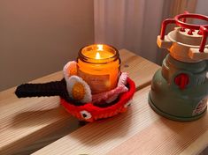 a candle is sitting on a table next to a cup holder with a knitted animal