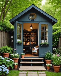 a small blue shed sitting in the middle of a lush green yard with potted plants