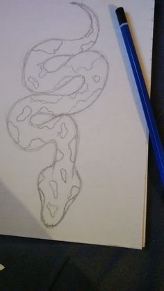 a drawing of a snake on paper next to a pencil