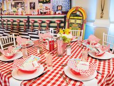 a red and white checkered table cloth with plates and cups on it is set for a party