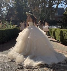 a woman in a wedding dress is walking down the street with other people behind her