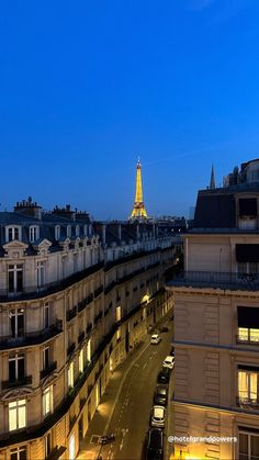 the eiffel tower is lit up in the distance from an apartment building at night