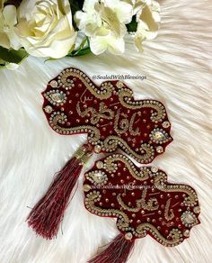 two red fan shaped brooches sitting on top of a white fur covered floor