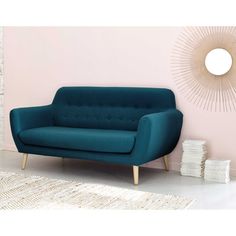 a blue couch sitting in front of a pink wall with a sun mirror on it