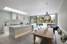 a modern kitchen and dining room with wood flooring, white walls and ceiling lighting