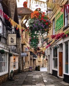 a narrow street with flowers hanging from the buildings