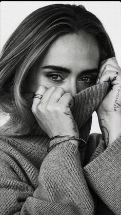 a black and white photo of a woman holding her hand to her face with both hands