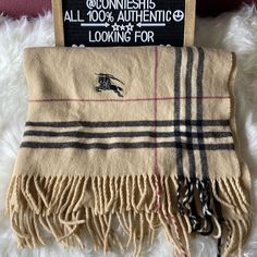 a burber scarf laying on top of a white furnishing floor next to a sign