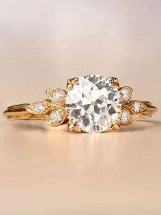 an engagement ring with a large diamond surrounded by smaller diamonds on the sides and gold band