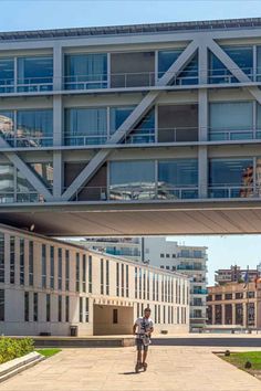 a man riding a skateboard under an overpass in front of a large building