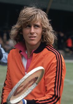 a man holding a tennis racquet on top of a tennis court with people in the background