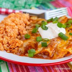 mexican food with rice and green onions on a red and white plate next to a fork