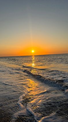 the sun is setting over the water at the beach