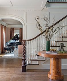 a grand piano sits in the center of this elegant entryway with wood flooring and white walls