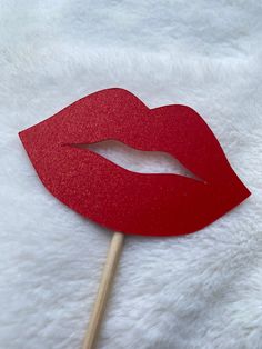 a red paper lip on a stick with a white fur surface in the foreground