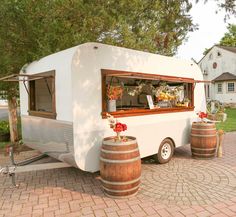 a food truck is parked on the side of the road next to two wine barrels