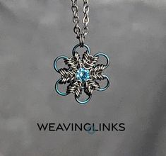 a silver necklace with a blue stone in the center and words weaving links on it