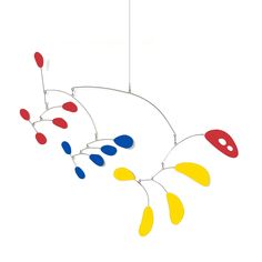 a multicolored wind chime hanging from a wire on a white background with red, yellow and blue colors