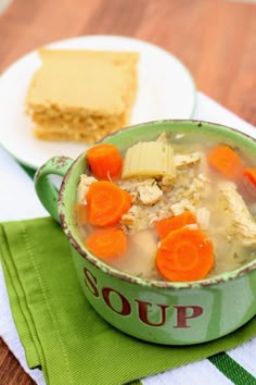 a bowl of chicken rice soup with carrots and crackers on the side, next to a slice of cake