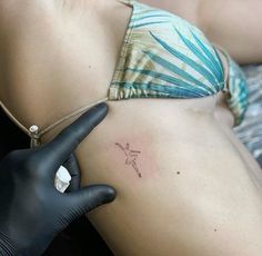 a woman with a tattoo on her stomach is pointing to the side while wearing black gloves