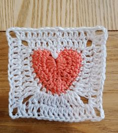 a crocheted square with a heart in the center on a wooden table top