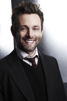 a man in a suit and tie smiling at the camera