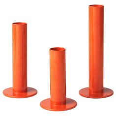 three orange plastic tubes are standing on pedestals