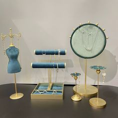 three mannequins and jewelry on display in front of a mirror with gold bases