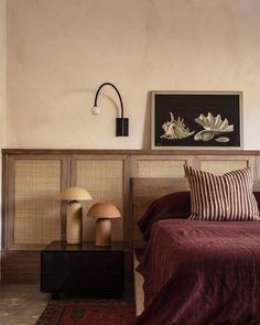 a bed with two lamps and a painting on the wall above it in a bedroom