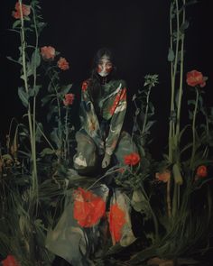 a woman is sitting in the middle of flowers