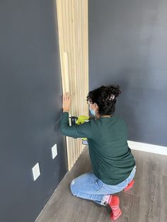 a woman kneeling down on the floor with a paint roller