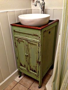 a bathroom sink sitting next to a green cabinet with a white bowl on top of it