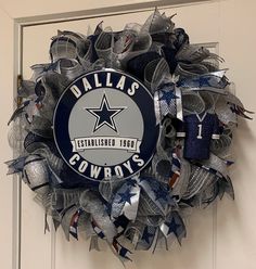 a wreath that is hanging on a door with the word cowboys painted on it and an image of a football team