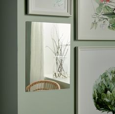 four framed pictures hang on the wall next to a wicker basket and vase with flowers