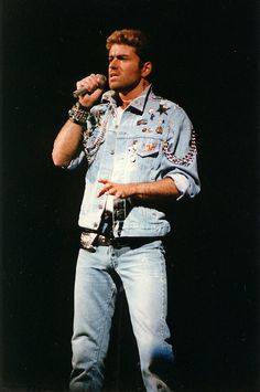 a man standing on top of a stage holding a microphone in his right hand and looking off to the side