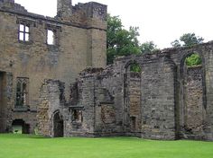 an old stone building sitting on top of a lush green field