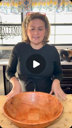 a woman standing in front of a wooden bowl