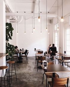 two people sitting at tables in an open room with exposed ceilings and wooden stools