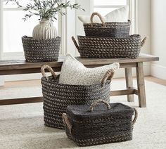 three baskets with handles are sitting on a table in front of a vase and window