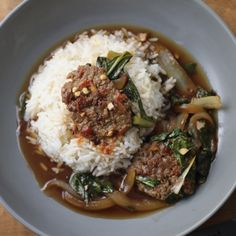 a white plate topped with meat and vegetables covered in gravy on top of rice