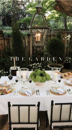 an outdoor table set for two with candles and plates