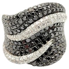 Ring size: 8 The dazzling diamond band ring exudes contemporary elegance. Bursting with sparkle, this black and white pave diamond piece offers beautiful contrast, modern design and chic sophistication. The wide style fills the finger with sparkle from end to end while the subtle wave design gives added interest to the piece. Dress this up or down, it will be the perfect addition to any look. Ring size: 8 Weight: 12.2 grams Metal: 14 Karat White Gold Natural Diamonds: 1.86 ctw Diamond cut: Round Luxury Black Diamond Ring With Brilliant Cut, Diamond White Ring With Black Diamonds, White Gold Diamond Ring With Black Diamonds, Fine Jewelry Diamond White Ring With Black Diamonds, Fine Jewelry Diamond Ring With Black Diamonds, Diamond White Rings With Black Diamonds, Luxury Silver Diamond Ring With Black Diamonds, Luxury Black Diamond Ring With Pave Setting, Luxury Black Diamond Round Ring