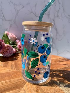 a glass jar with a straw in it sitting on a table next to some flowers