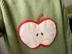 an apple appliqued on the back of a green sweater