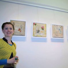 a woman is standing in front of some pictures on the wall and holding a remote control