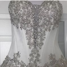 the back of a white wedding dress with silver beadings and flowers on it