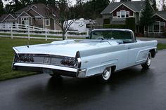 an old classic car parked on the side of the road in front of some houses