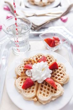 waffles with strawberries and whipped cream on them are sitting on a plate