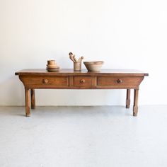 an old wooden table with two bowls on it and one bowl sitting on the top